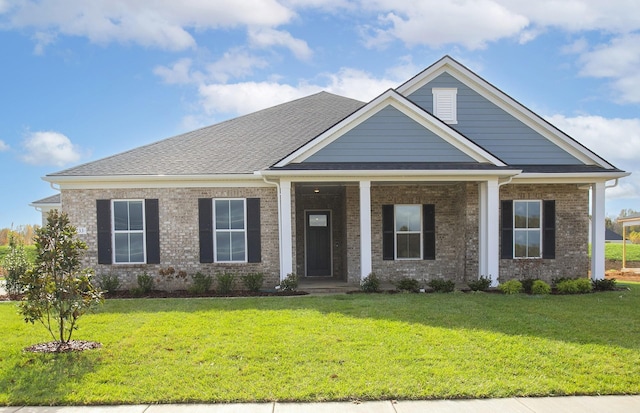 craftsman-style house with covered porch, brick siding, roof with shingles, and a front yard