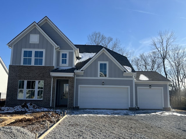 view of front of home with a garage, brick siding, board and batten siding, and gravel driveway