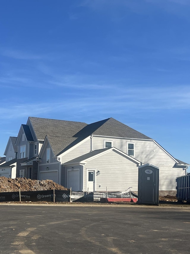 view of front facade featuring a garage and roof with shingles