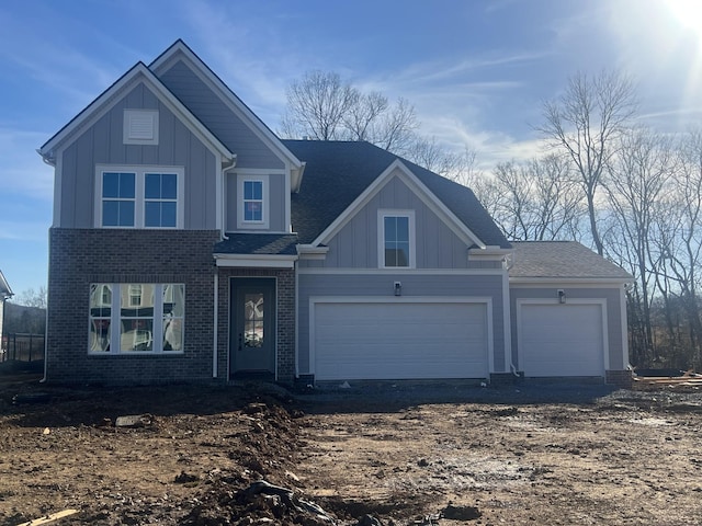 view of front of property featuring board and batten siding, brick siding, driveway, and a garage