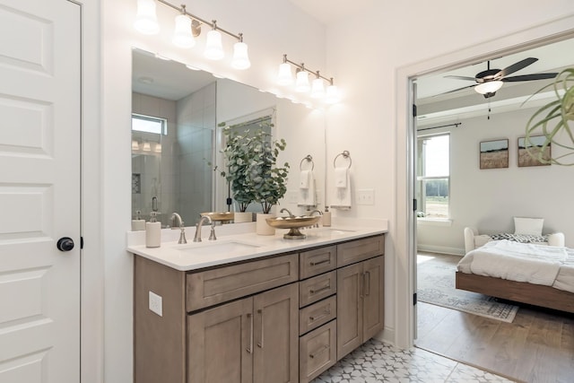 full bathroom featuring ensuite bathroom, a sink, a ceiling fan, double vanity, and a stall shower