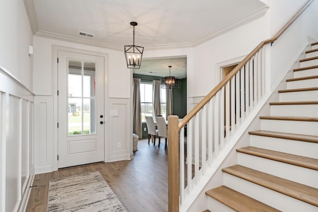 foyer entrance with stairs, wood finished floors, visible vents, and crown molding