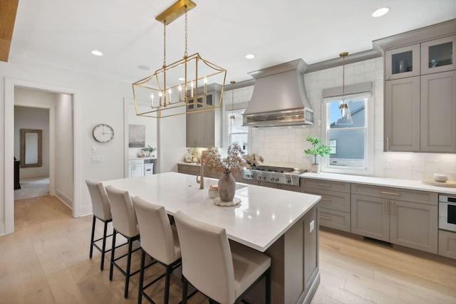 6324 Percheron Ln, Arrington, TN 37014 - kitchen with stainless steel gas cooktop, light wood finished floors, custom range hood, decorative backsplash, and gray cabinetry