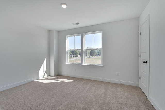 empty room with visible vents, light carpet, and baseboards