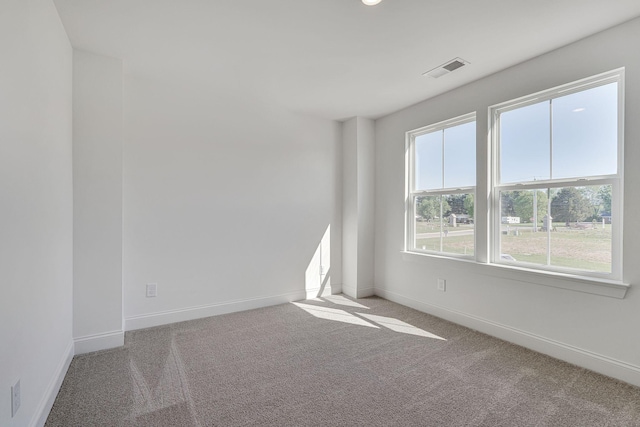 empty room featuring carpet, visible vents, and baseboards