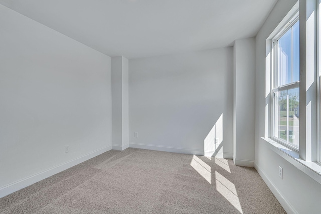 spare room featuring baseboards and light colored carpet