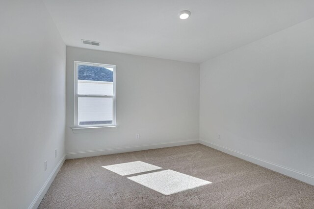 carpeted empty room featuring visible vents and baseboards