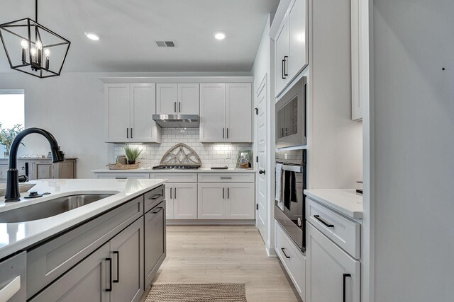 kitchen with visible vents, under cabinet range hood, light countertops, appliances with stainless steel finishes, and a sink