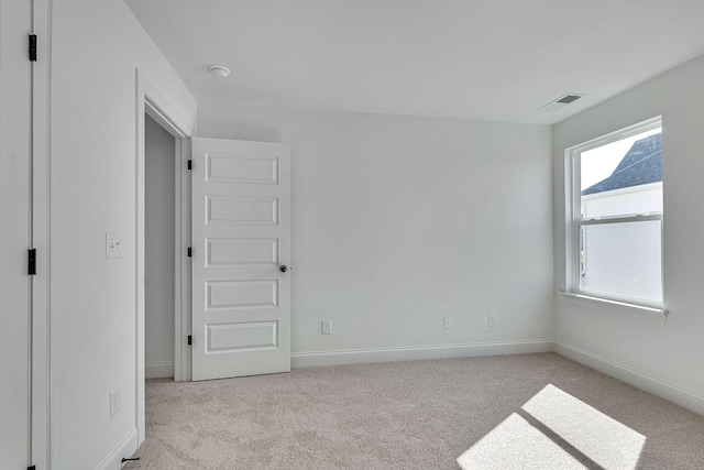 unfurnished bedroom featuring baseboards, visible vents, and light colored carpet