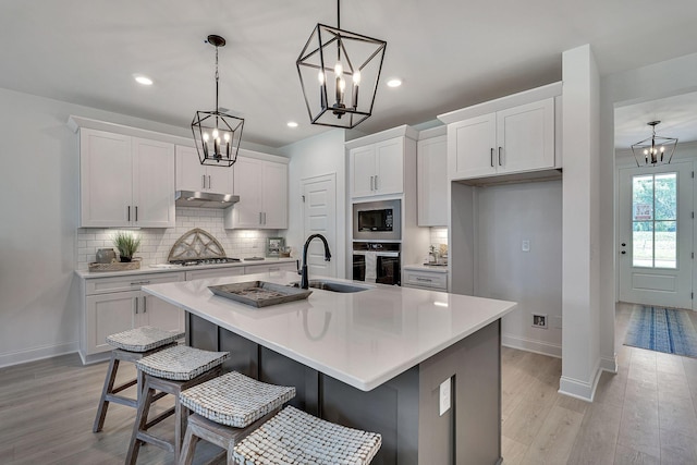 kitchen with a chandelier, oven, built in microwave, and a sink