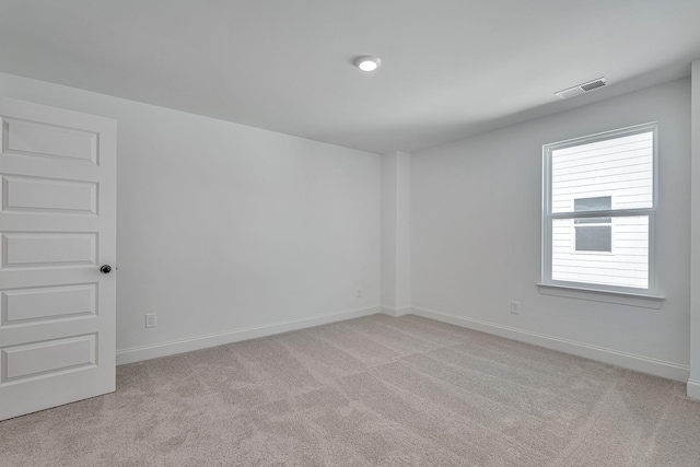 empty room featuring light colored carpet, visible vents, and baseboards