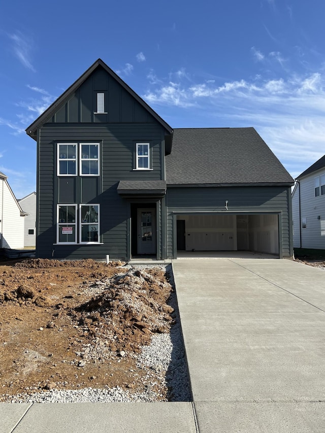 view of front of home with a garage, driveway, board and batten siding, and roof with shingles