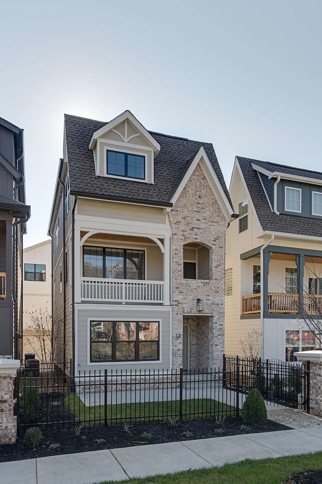 view of front of home featuring a fenced front yard, brick siding, and roof with shingles