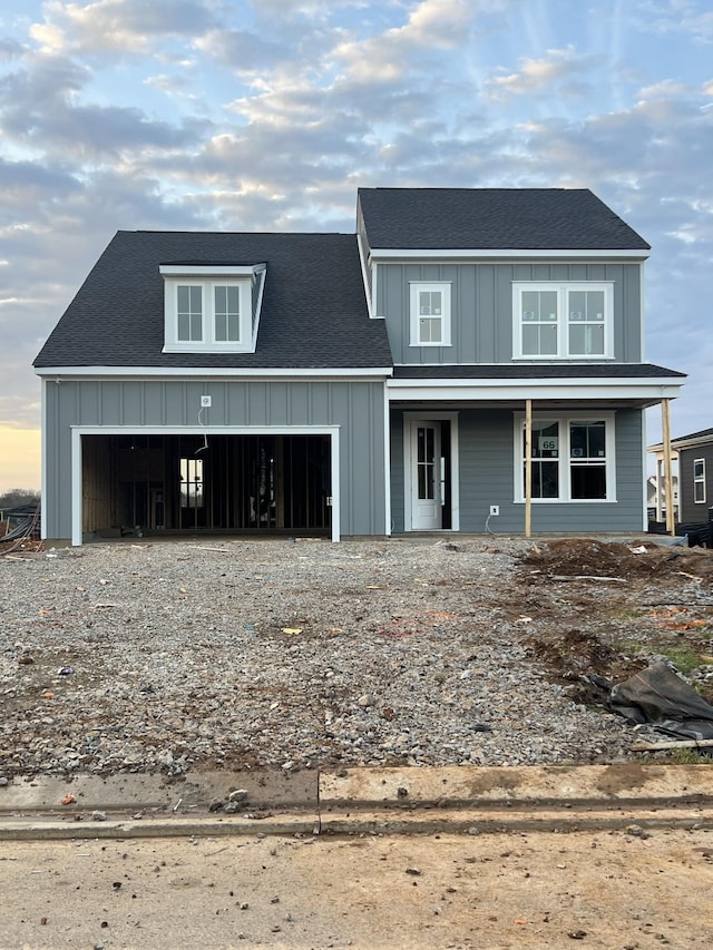 view of front of home with covered porch, driveway, board and batten siding, and an attached garage