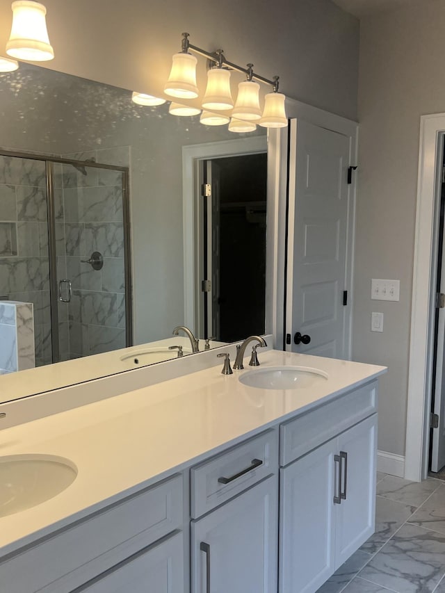 full bath with a sink, marble finish floor, a shower stall, and double vanity