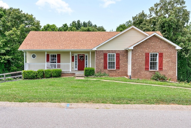 single story home with brick siding, covered porch, fence, and a front yard