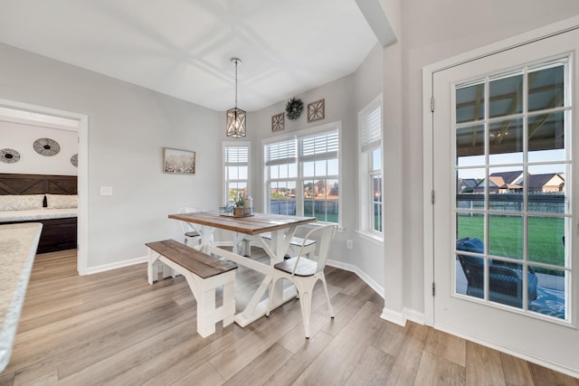 dining space with a chandelier, light wood finished floors, and baseboards