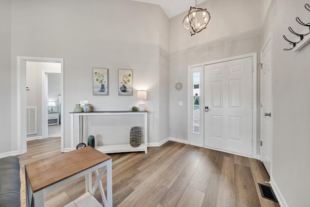 entryway featuring a towering ceiling, wood finished floors, visible vents, and baseboards