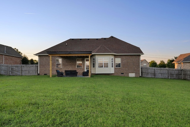 back of property at dusk with crawl space, a fenced backyard, and a lawn