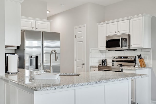 kitchen with appliances with stainless steel finishes, backsplash, a sink, and white cabinetry