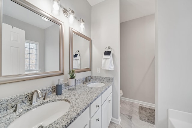 full bathroom featuring toilet, double vanity, baseboards, and a sink