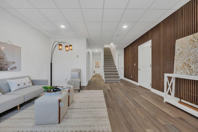 living room with wood walls, stairway, wood finished floors, and recessed lighting