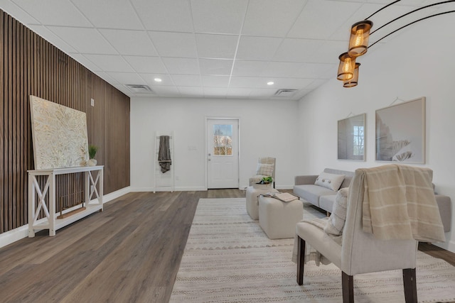 unfurnished living room featuring a paneled ceiling, visible vents, baseboards, and wood finished floors