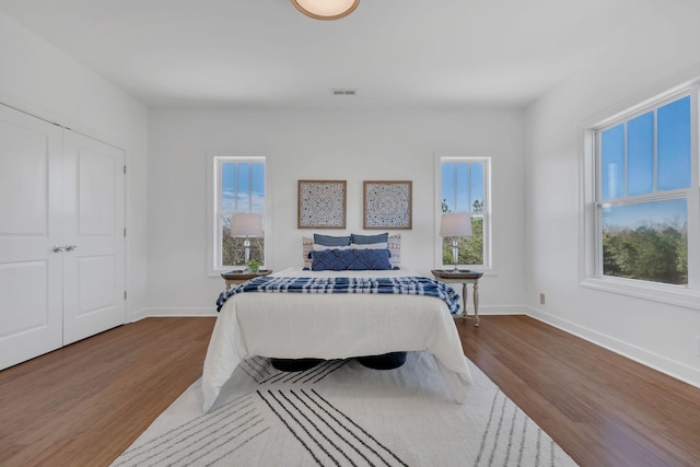 bedroom featuring multiple windows, wood finished floors, and visible vents