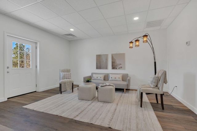 living area with wood finished floors, visible vents, and baseboards