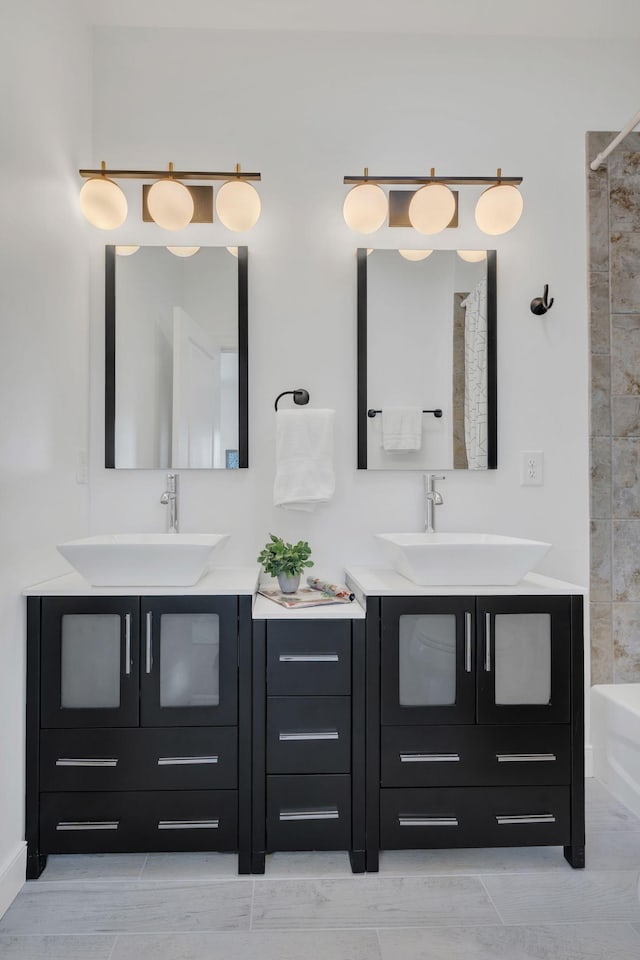 full bath featuring two vanities, a shower with shower curtain, and a sink