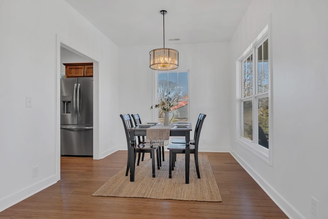 dining area featuring a notable chandelier, visible vents, baseboards, and dark wood-type flooring