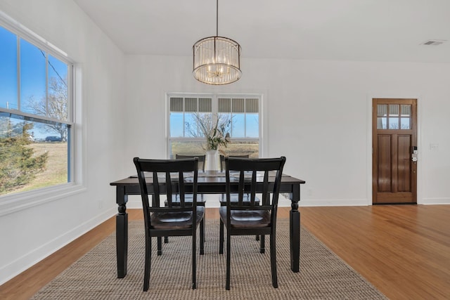 dining area featuring a chandelier, wood finished floors, visible vents, and a healthy amount of sunlight