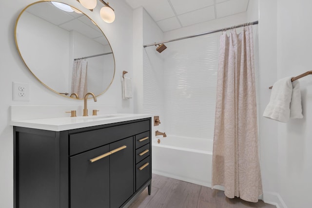 full bathroom featuring a drop ceiling, shower / bath combo with shower curtain, wood finished floors, and vanity