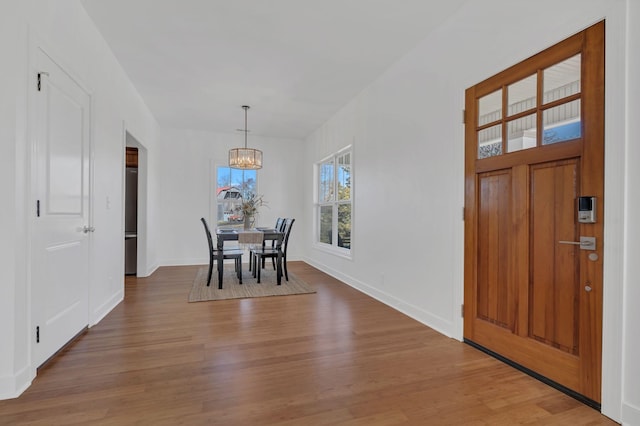 dining room featuring light wood-type flooring, baseboards, and an inviting chandelier