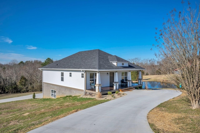 view of front facade featuring a porch, a front yard, a water view, and a shingled roof