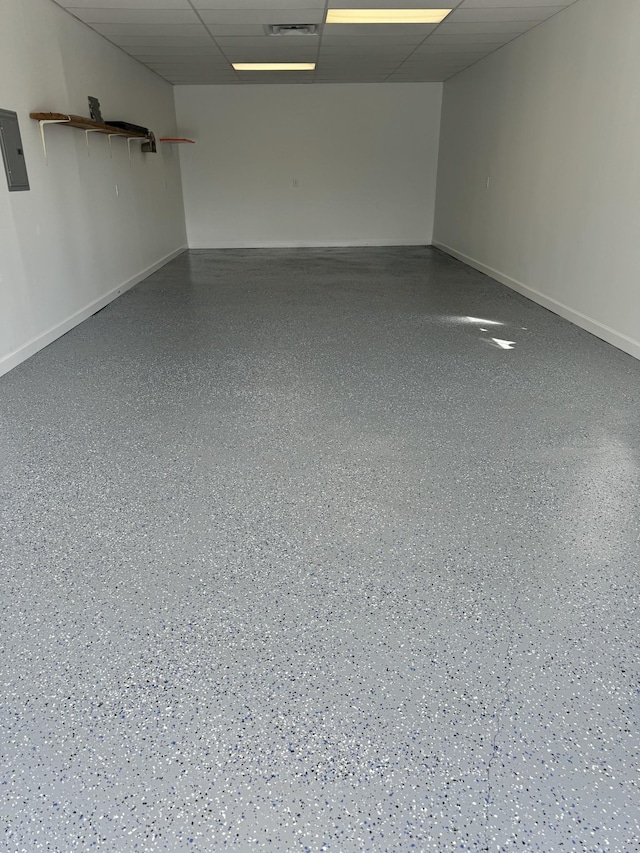 empty room featuring visible vents, a drop ceiling, electric panel, baseboards, and speckled floor