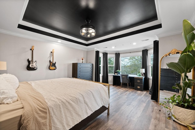 bedroom featuring ornamental molding, a tray ceiling, and wood finished floors