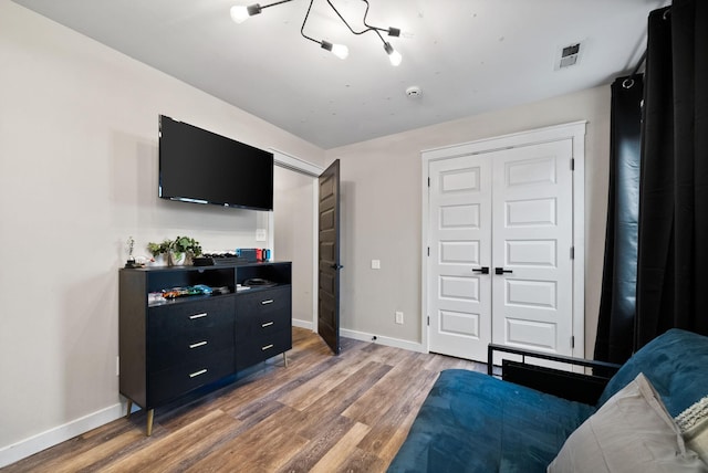 bedroom featuring light wood-type flooring, a closet, visible vents, and baseboards