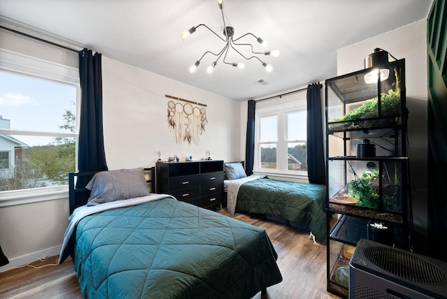 bedroom with a notable chandelier, visible vents, baseboards, and wood finished floors