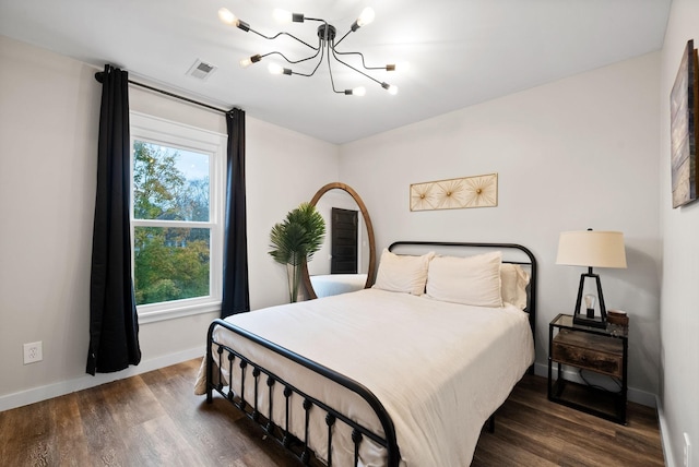 bedroom with an inviting chandelier, baseboards, visible vents, and wood finished floors