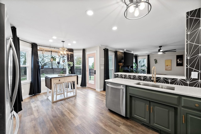 kitchen featuring stainless steel appliances, light countertops, a sink, and wood finished floors