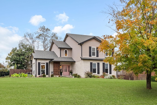 view of front of home with a front lawn, a shingled roof, fence, and brick siding