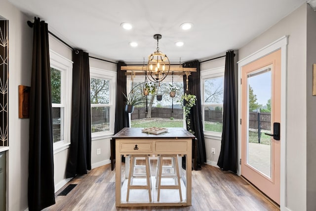 dining room with light wood-type flooring, a notable chandelier, plenty of natural light, and baseboards