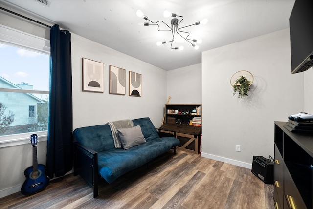 living area with baseboards, wood finished floors, and an inviting chandelier