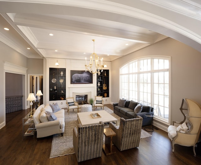 living area with a notable chandelier, dark wood-type flooring, ornamental molding, beam ceiling, and a glass covered fireplace