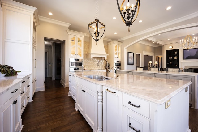 kitchen featuring arched walkways, a spacious island, a sink, stainless steel oven, and dark wood-style floors