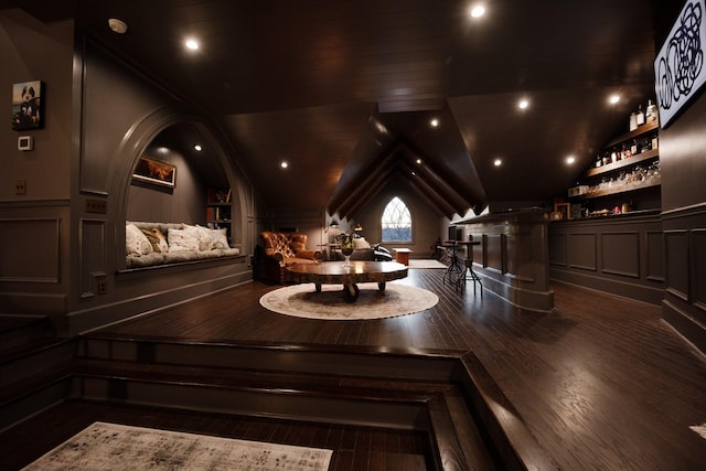 interior space with recessed lighting, a decorative wall, vaulted ceiling, a bar, and wood finished floors