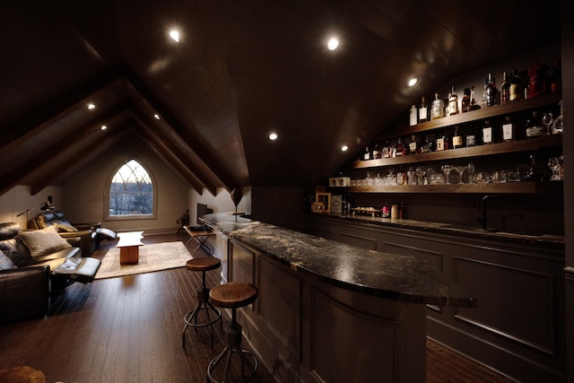 bar with wet bar, wood-type flooring, a sink, and lofted ceiling