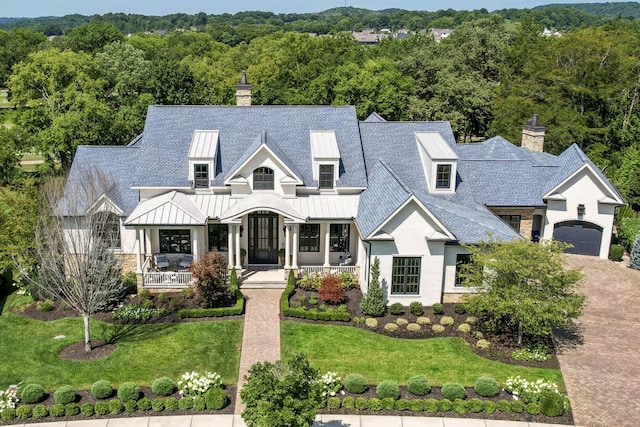 modern farmhouse style home with a standing seam roof, covered porch, metal roof, and a chimney