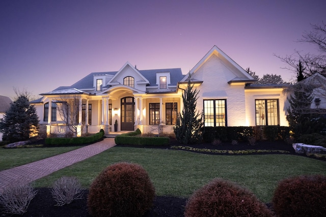 view of front of home with covered porch, french doors, and a front lawn